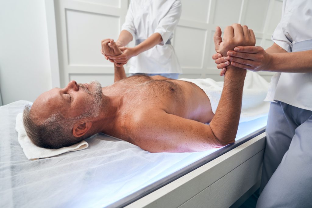 Bearded man having hand massage in spa salon